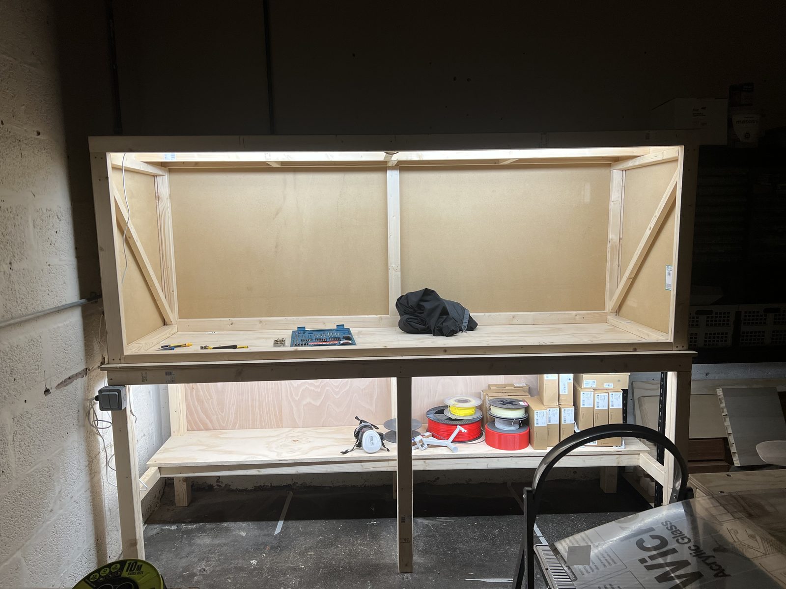 A timber workbench built inside the makerspace, with a lit upper cabinet and storage below